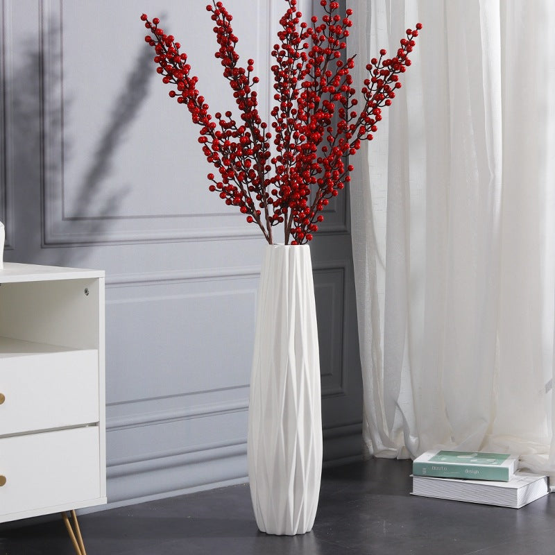 White sculptural wavy textured floor vase styled with tall red berry branches in a modern interior