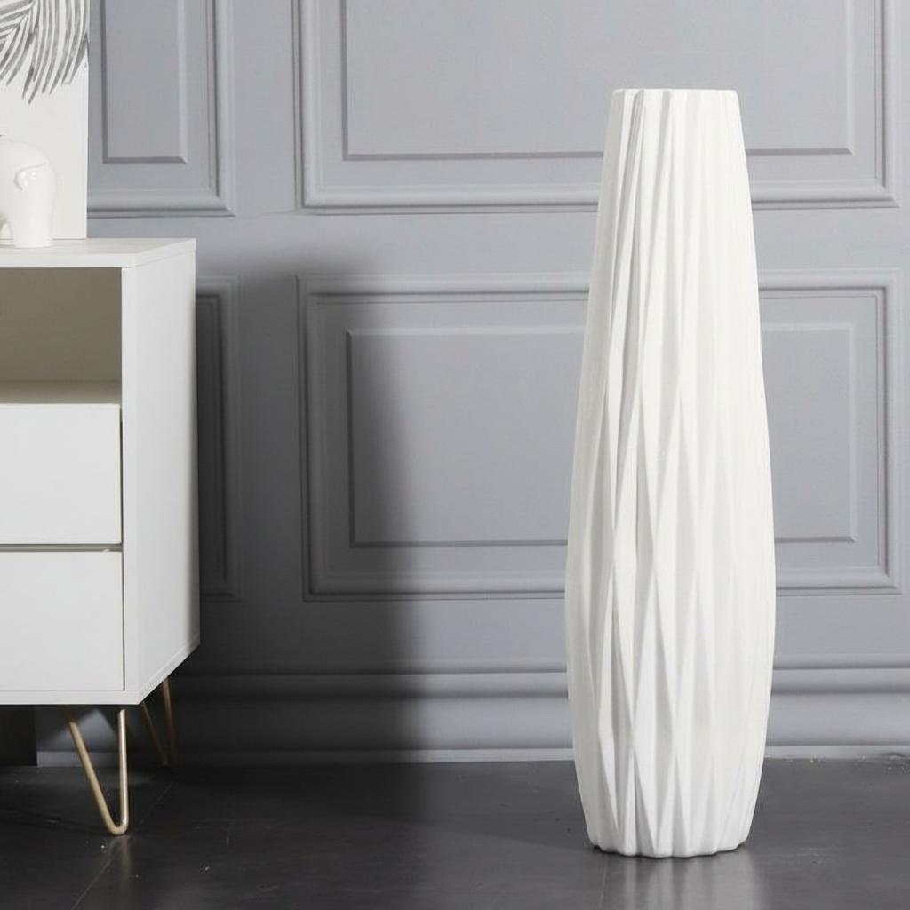 White sculptural wavy floor vase displayed empty against a paneled wall