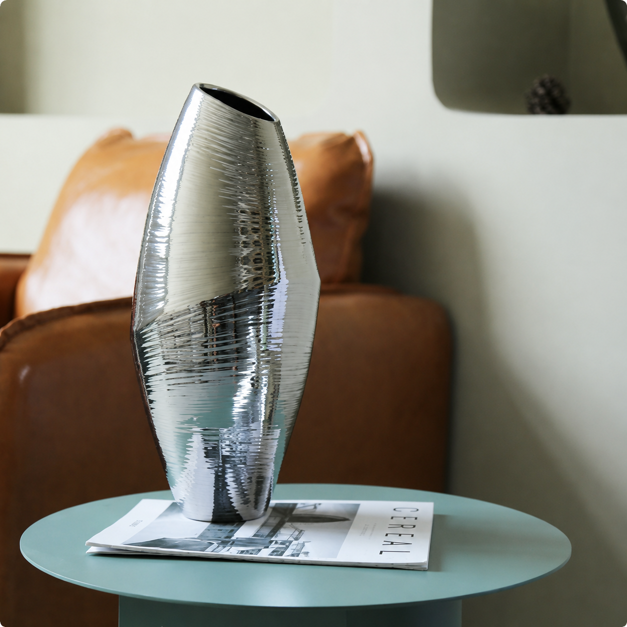 Silver ceramic vase on green side table with modern living room decor