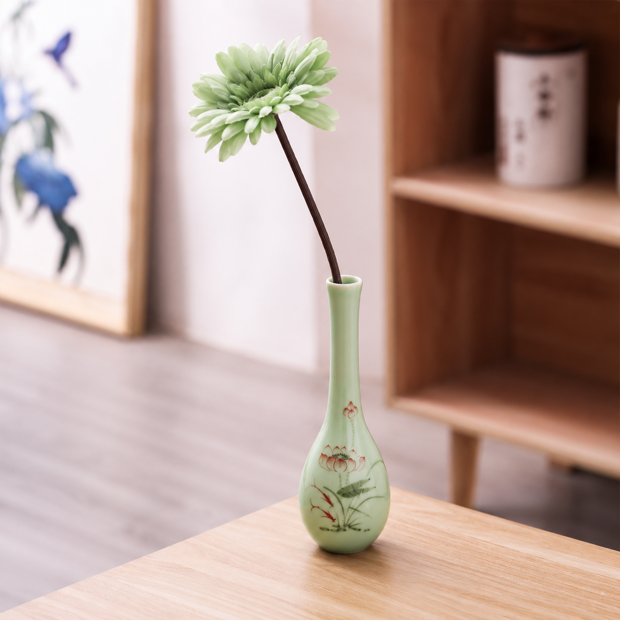 Celadon green slim ceramic bud vase with lotus artwork holding a single green flower stem