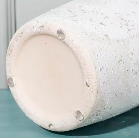 Bottom view of speckled white ceramic vase showing base and protective feet