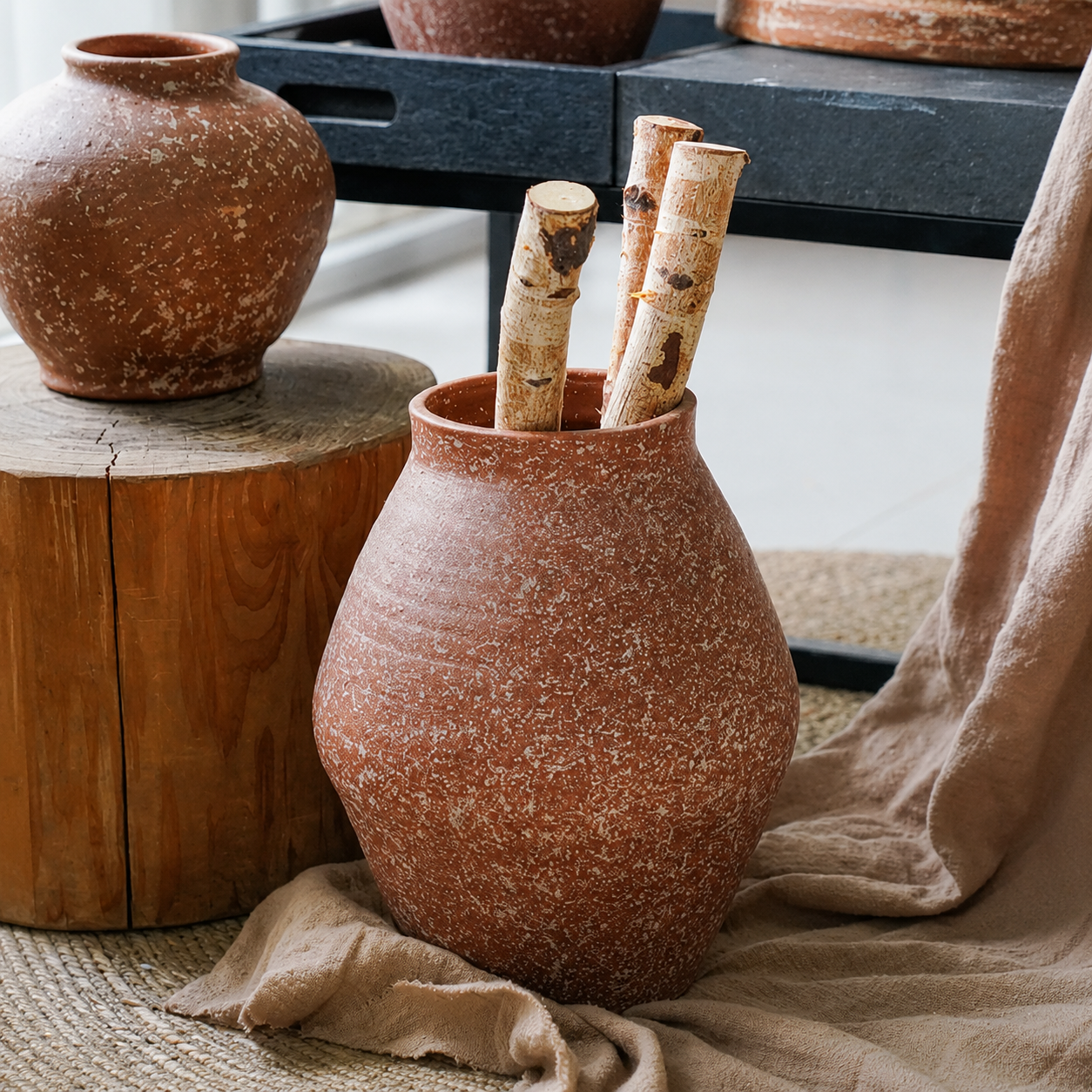 Terracotta ceramic vase with wooden branches on rustic fabric and natural decor