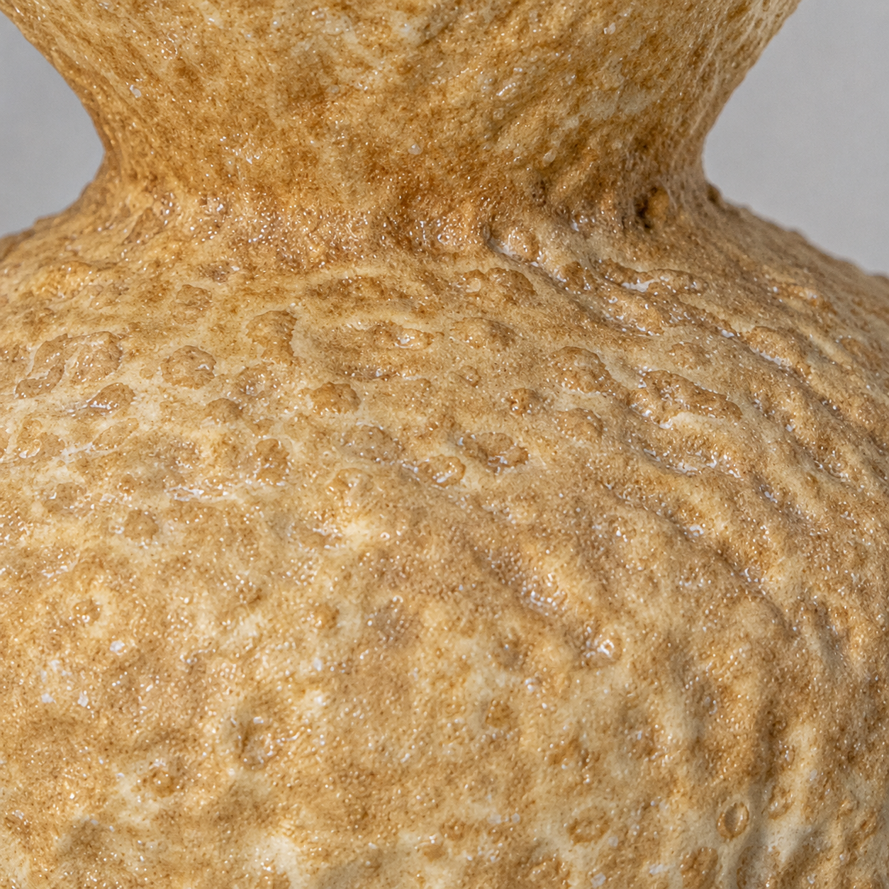 Close up of organic textured glaze on beige ceramic vase