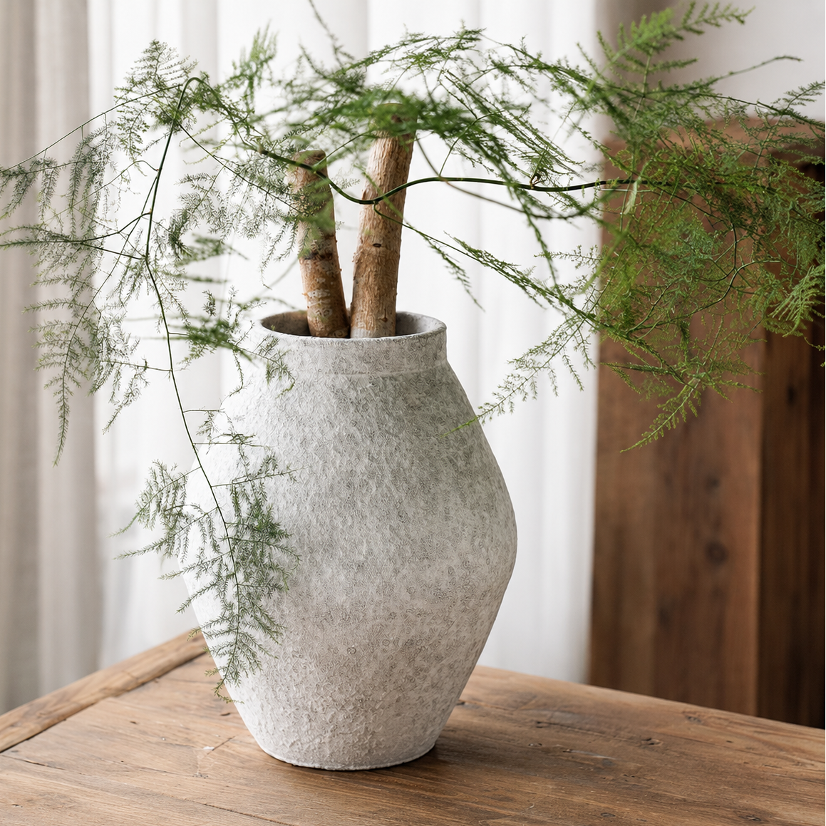 bulb shape textured ceramic vase with greenery on wooden table in neutral interior