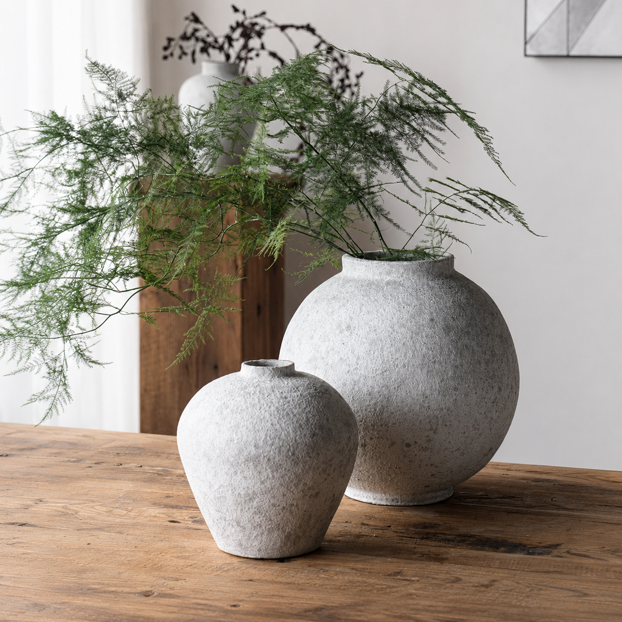 Textured ceramic vases styled with airy greenery on rustic wooden table