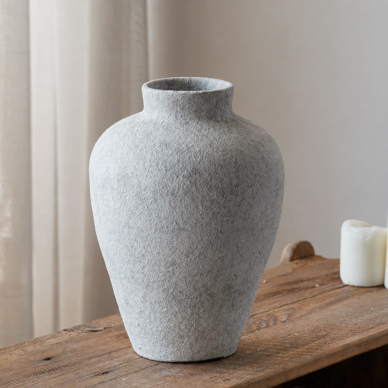 Tall textured ceramic vase with stone look finish on wooden table