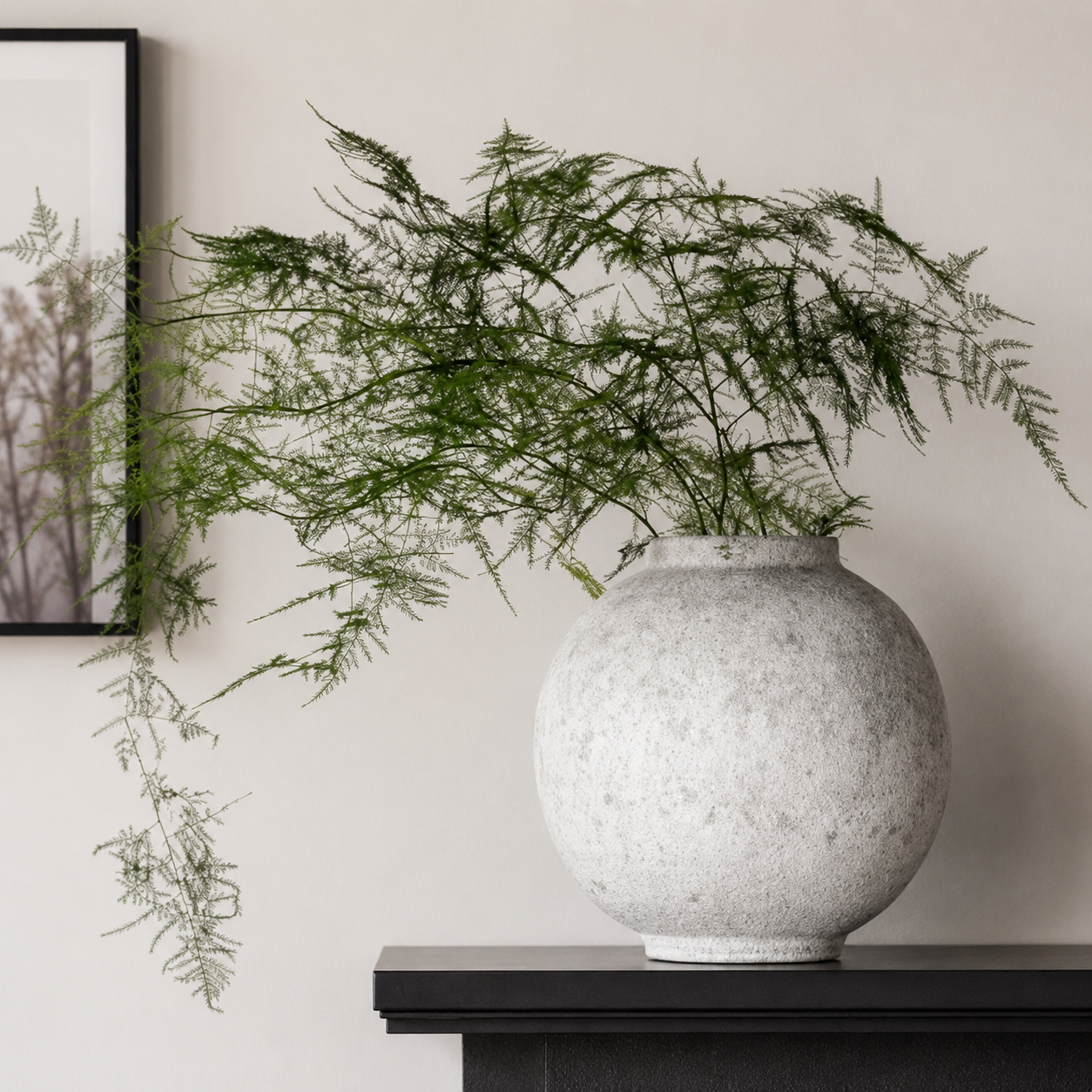 Round textured ceramic vase with delicate greenery on dark console table