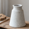 Tapered textured ceramic vase on wooden table with rustic neutral background