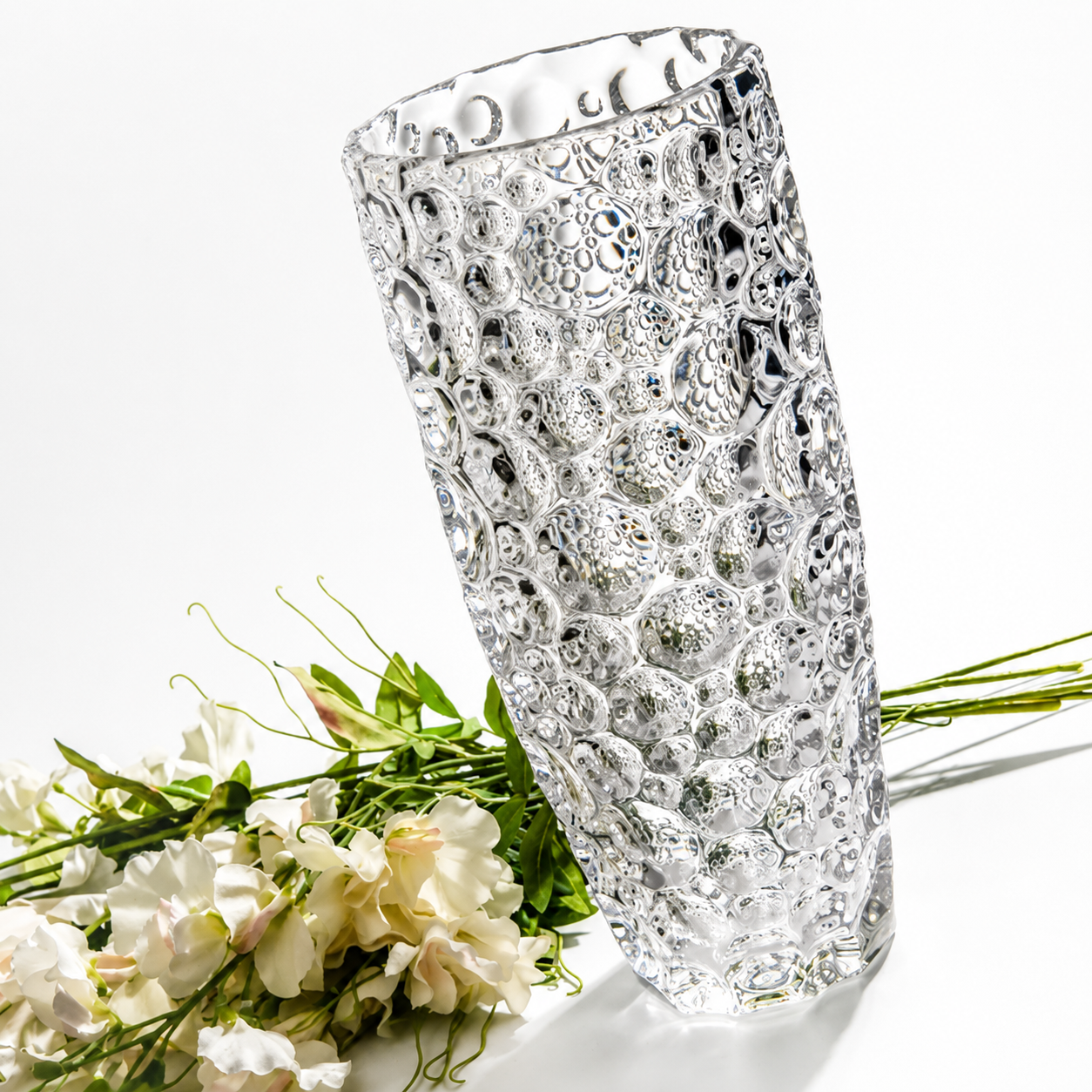 Clear bubble textured glass vase styled beside white flowers