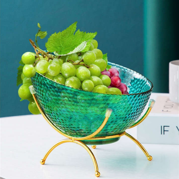 Teal textured glass fruit bowl with gold rim and gold stand filled with grapes