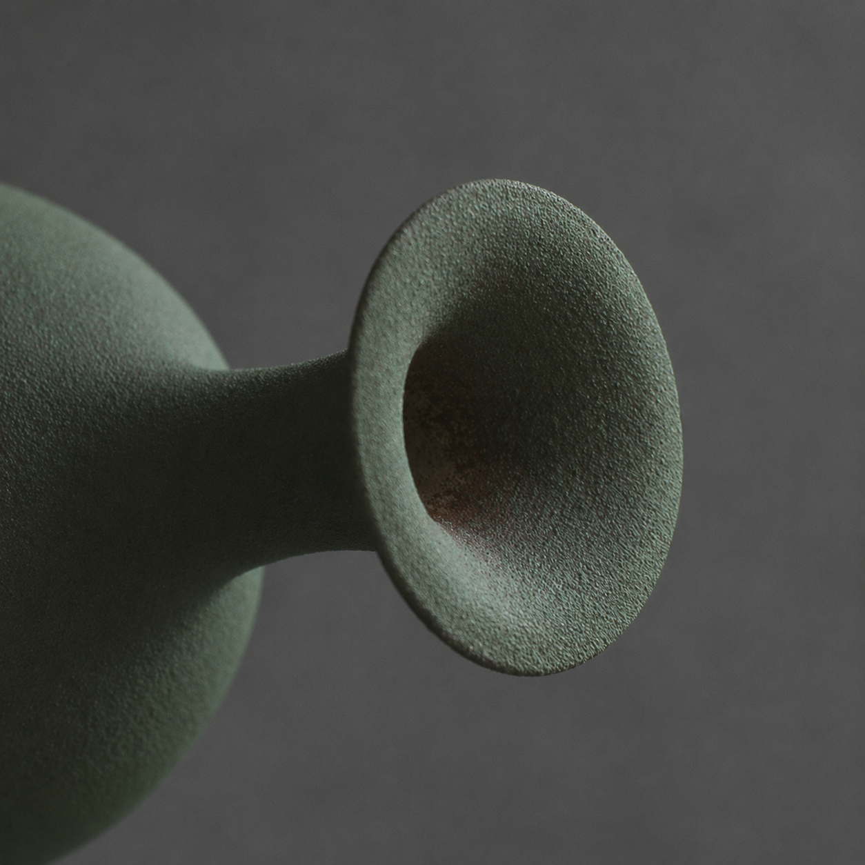 Close up of flared rim on textured green ceramic bottle vase