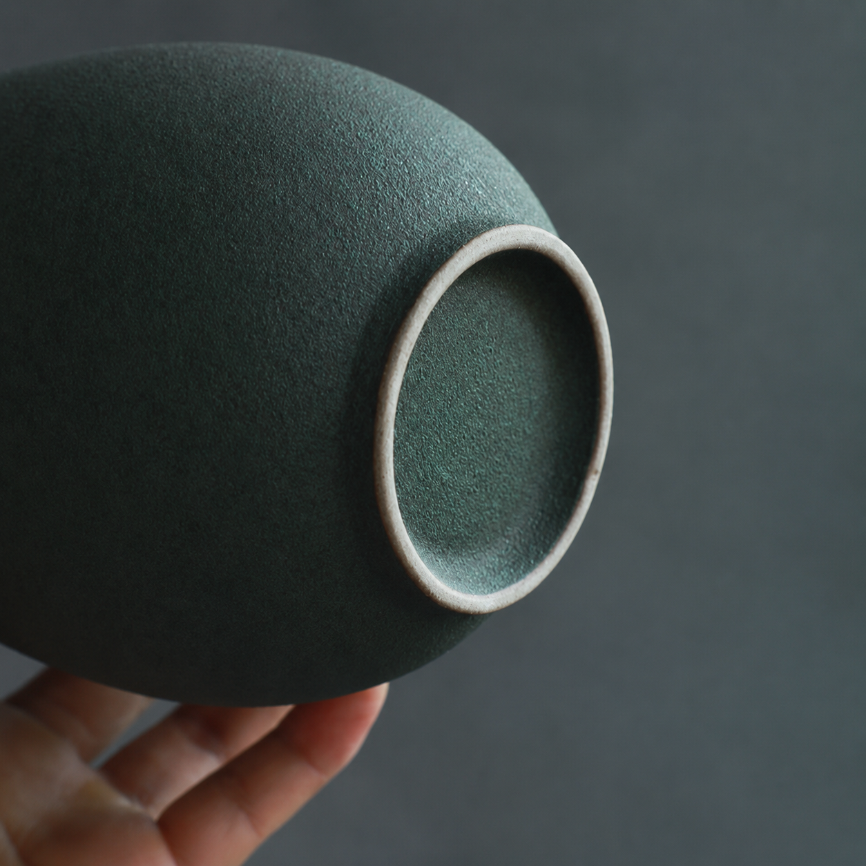 Close up of footed base on textured green ceramic vase