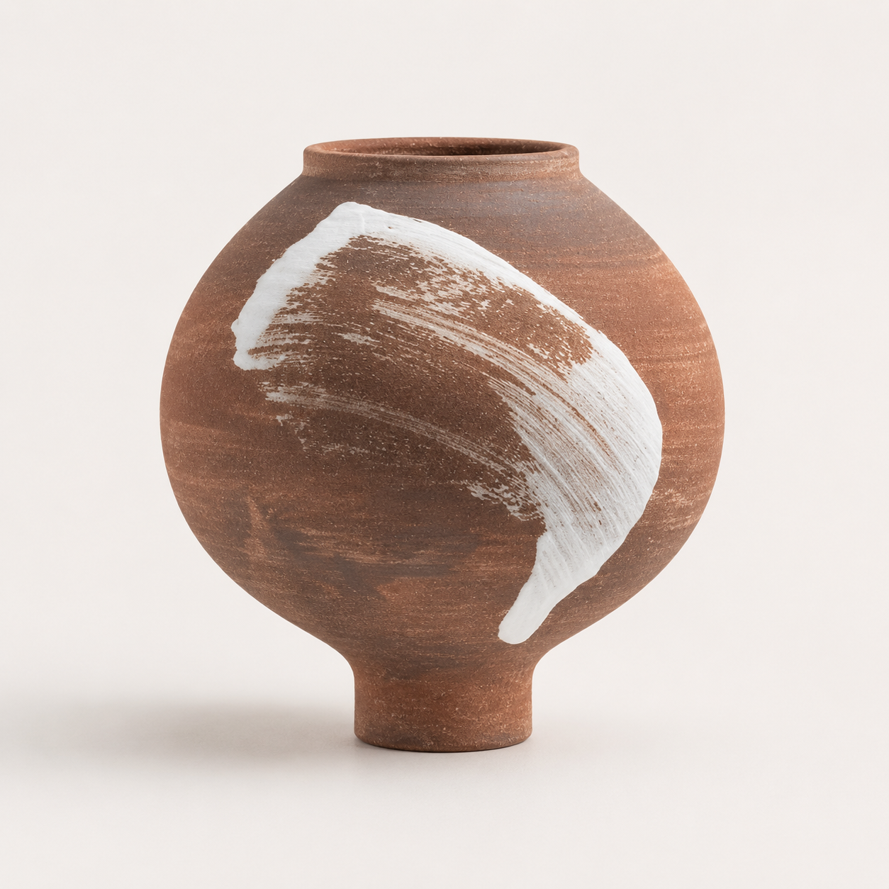 Short round terracotta ceramic vase with white brushstroke accent on white background