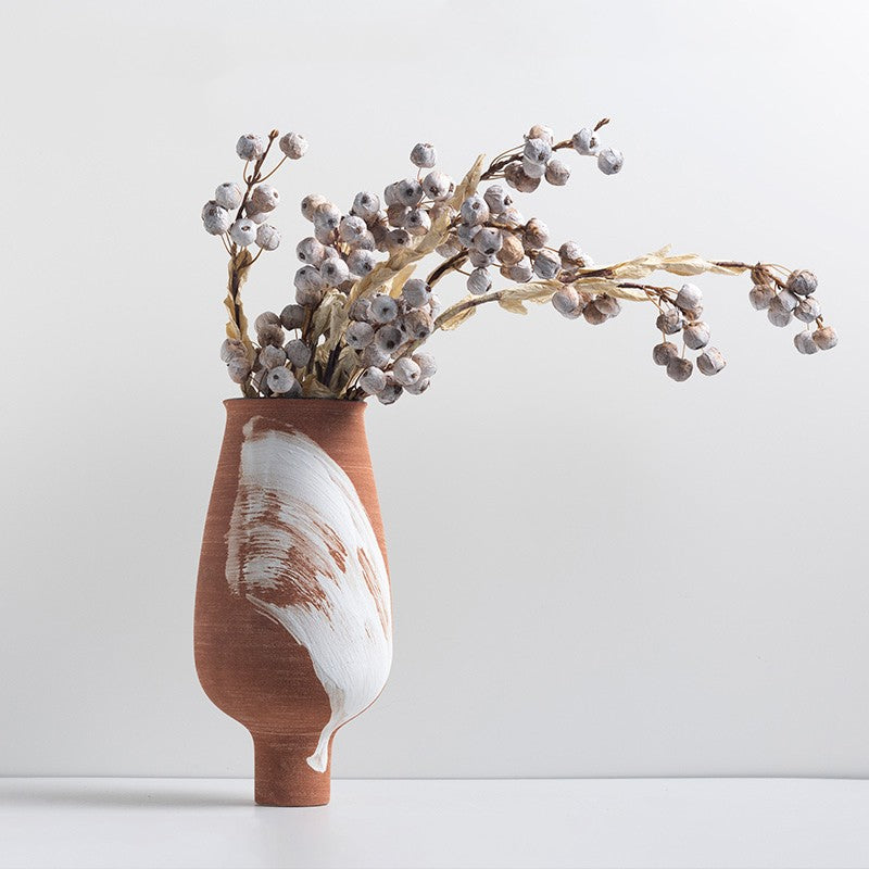 Tall terracotta ceramic vase with white brushstroke detail and dried branches