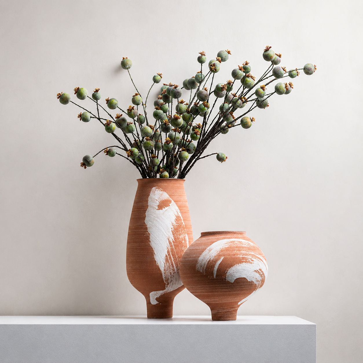 Terracotta ceramic vase set with berry branches on minimalist white pedestal