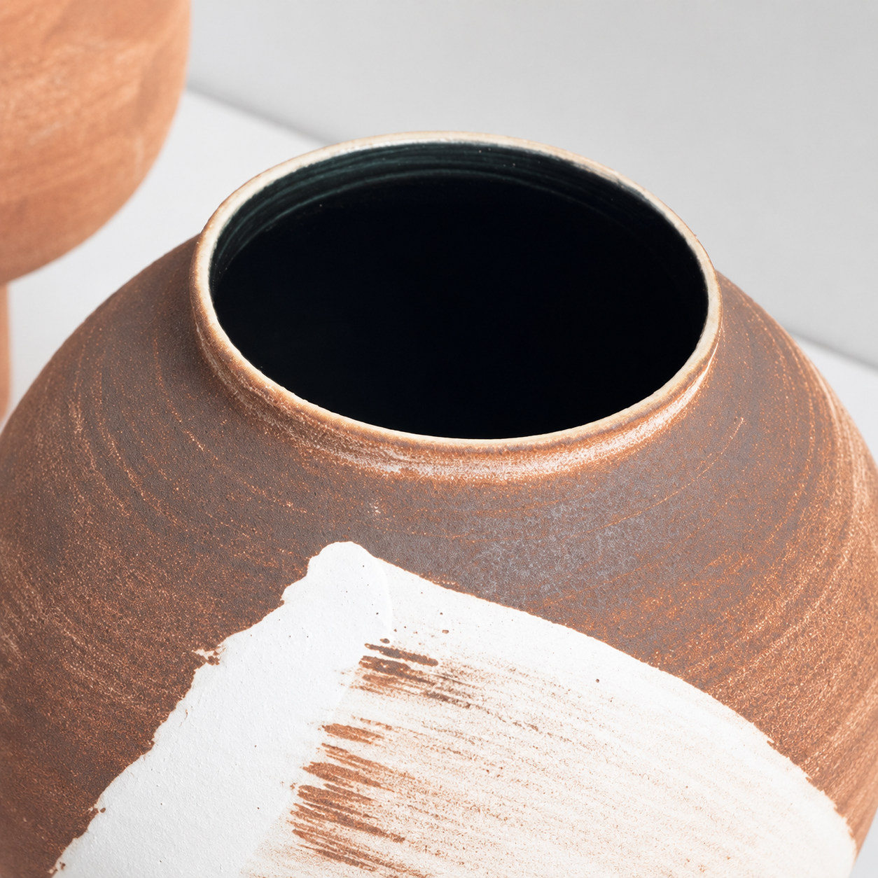 Close-up of terracotta ceramic vase opening with textured matte finish