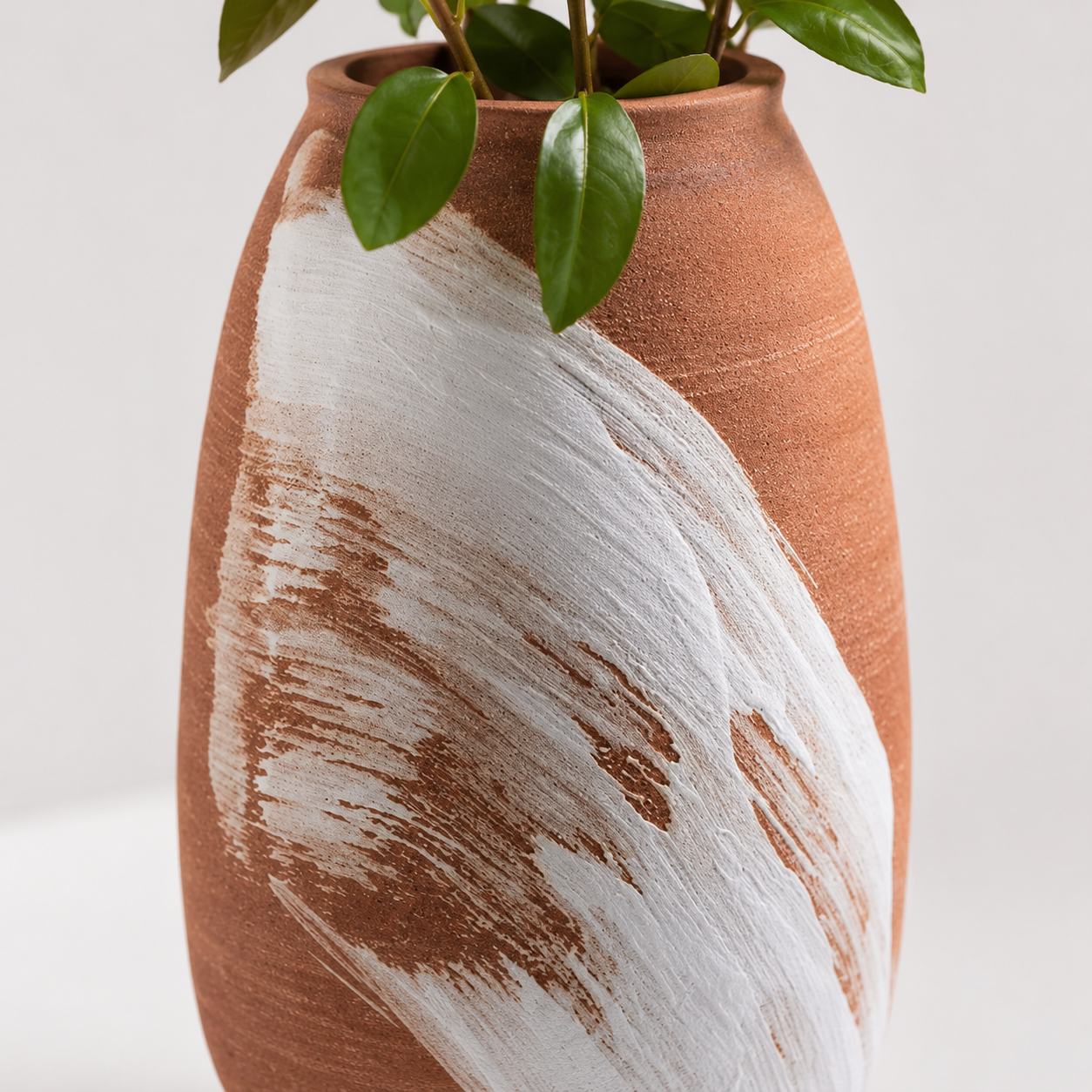 Close-up of white brushstroke detail on textured terracotta ceramic vase