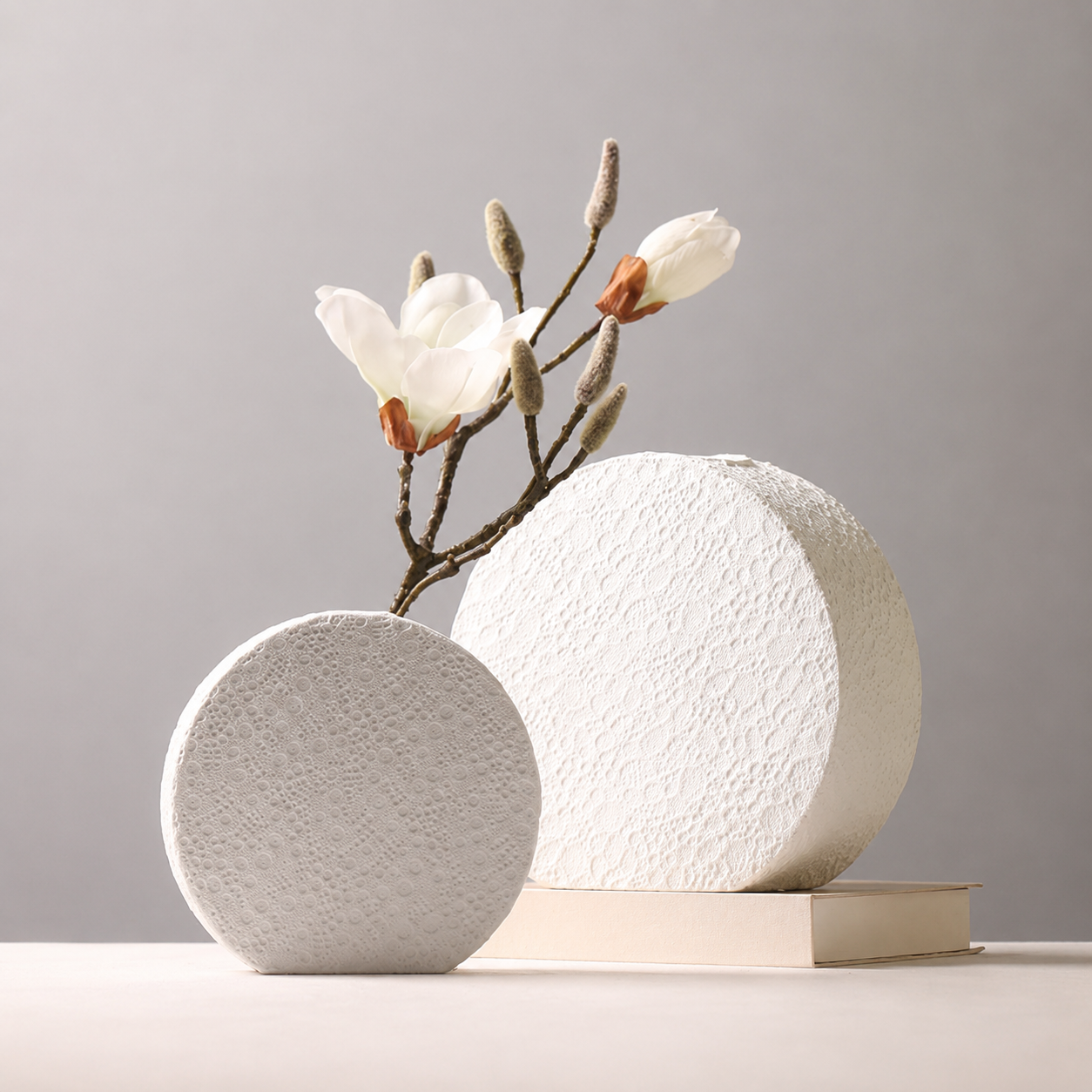 Large and medium textured white ceramic round vases with white magnolia branches