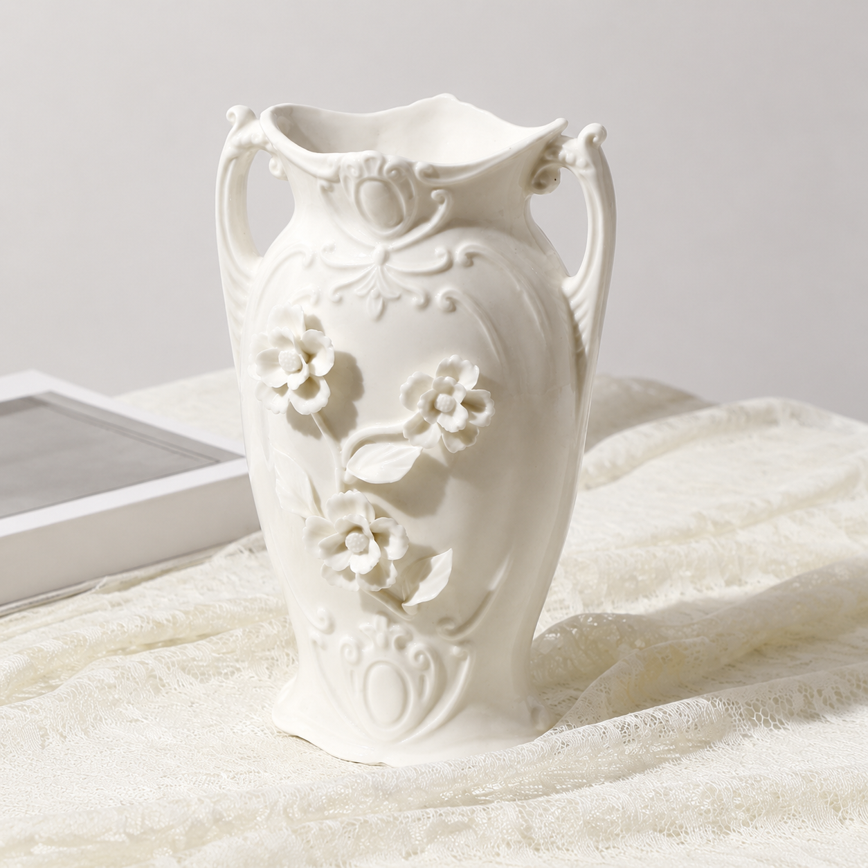 White ceramic Daisy vase with raised floral details on lace fabric