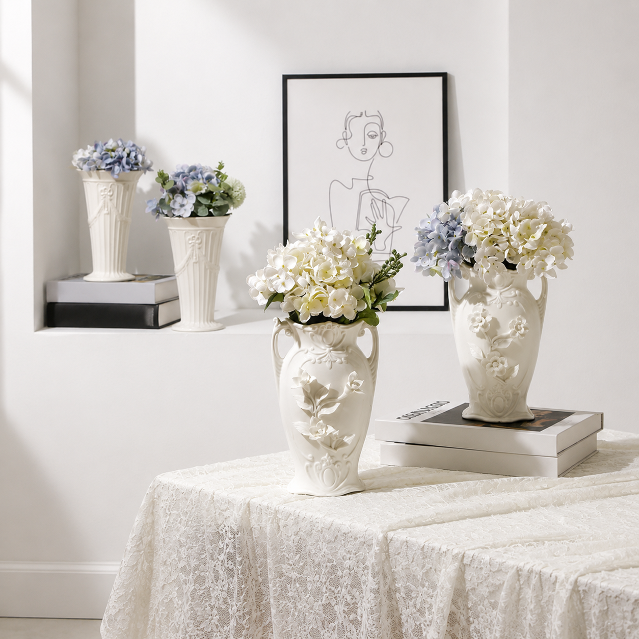 White ceramic floral vases styled with hydrangeas, books, and framed wall art