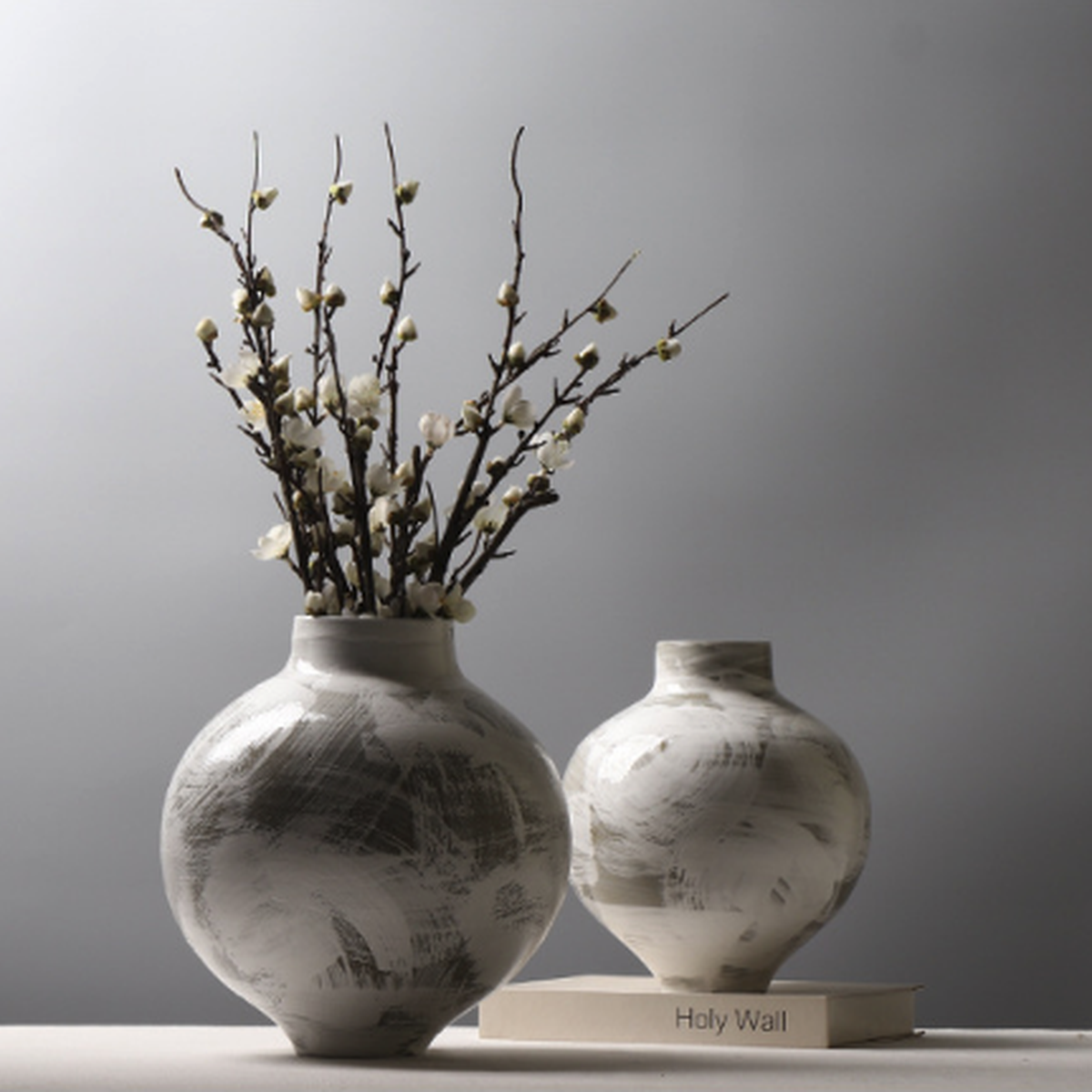 Two neutral ceramic vases styled with white blossom branches for minimalist decor