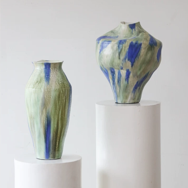 Abstract glaze ceramic vases in wabi sabi style displayed on white pedestals