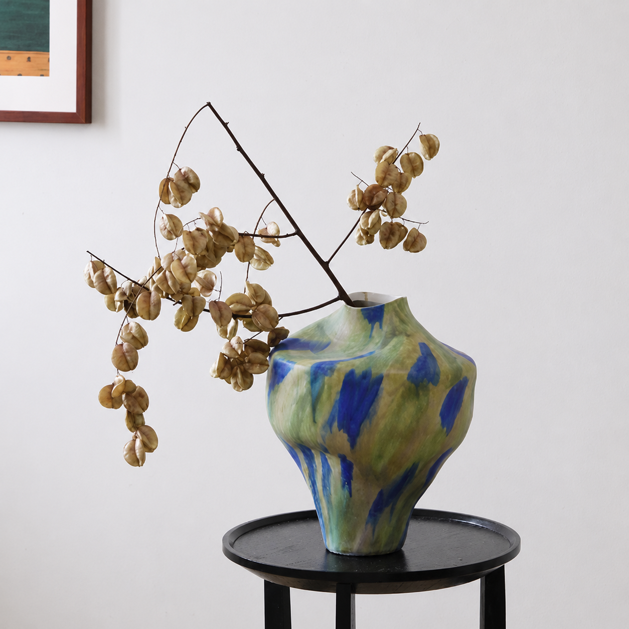 Wabi sabi inspired ceramic vase with abstract glaze styled with dried branches on side table