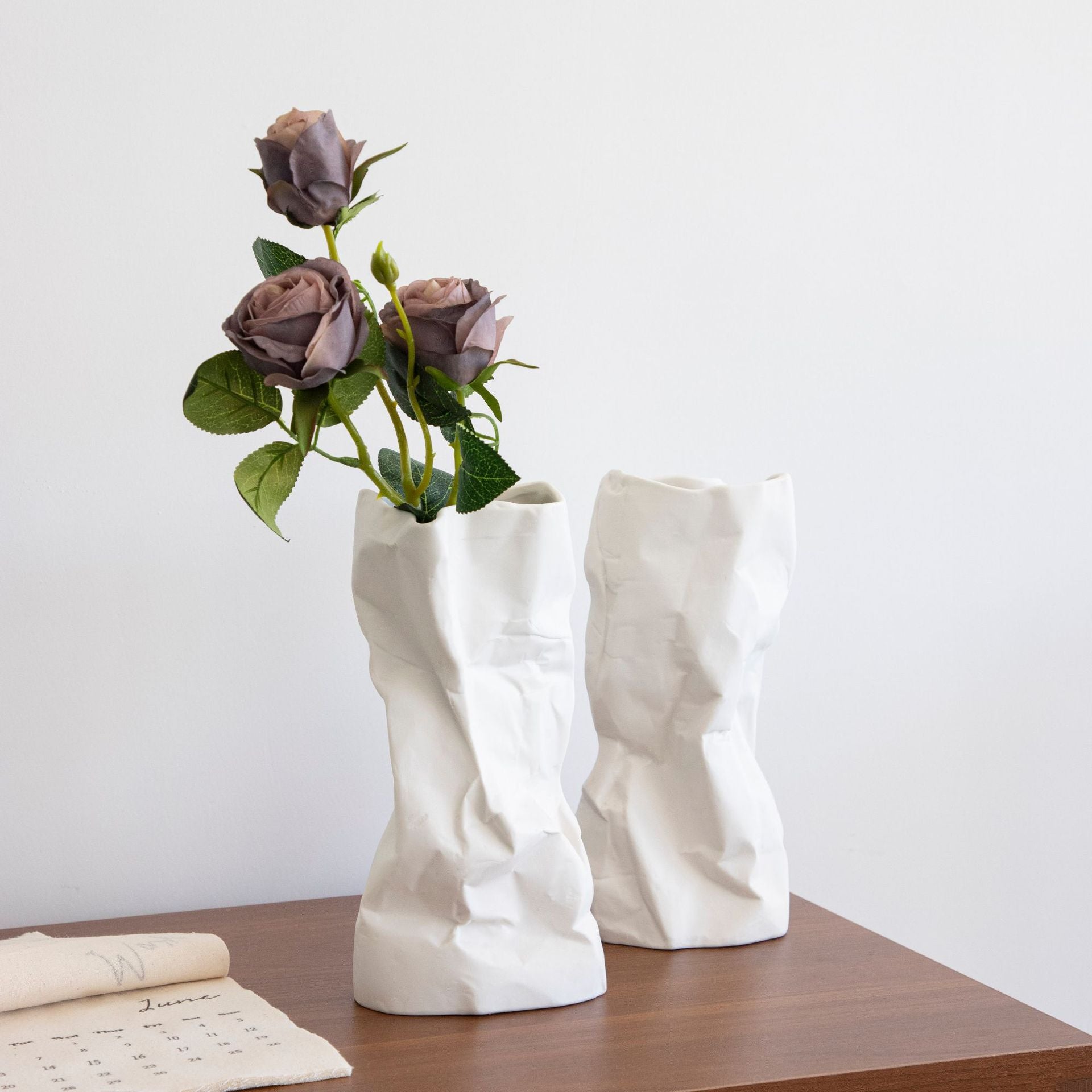 White ceramic crumpled vases with mauve and blush flowers on a tabletop
