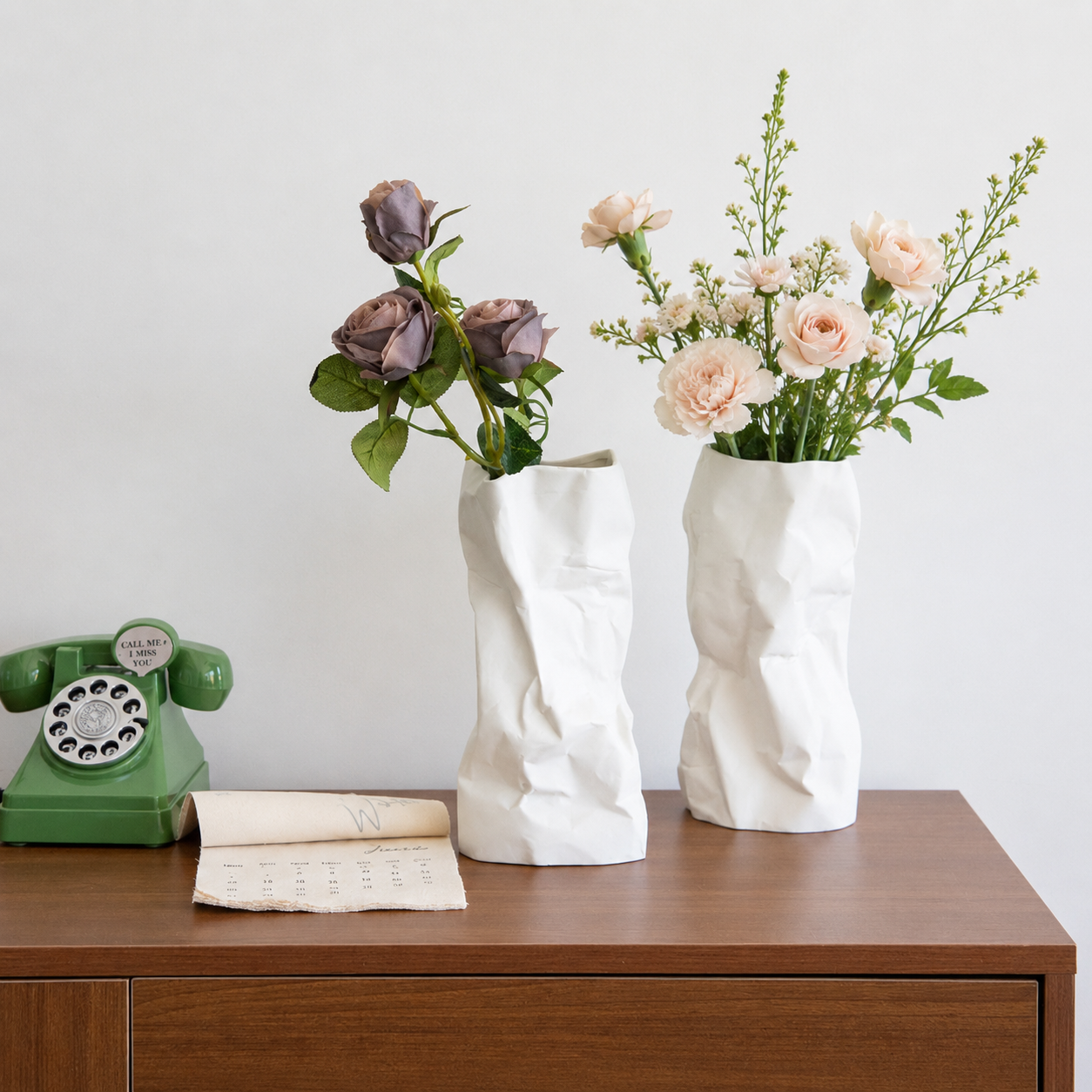 White ceramic crumpled vases with different flowers on a wooden console table