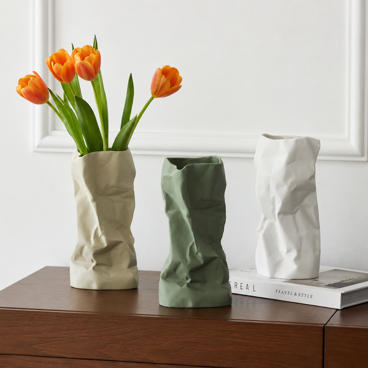 Crumpled ceramic vases in beige, green, and white with orange tulips