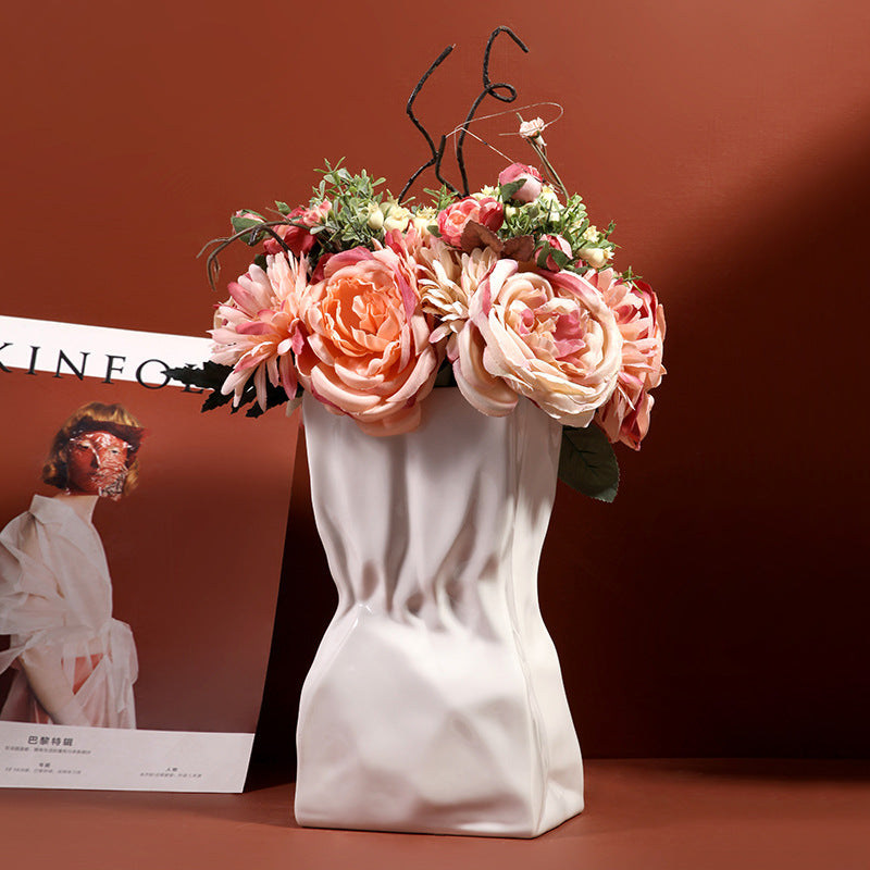 White ceramic crumpled vase with blush pink flowers in a modern styled interior