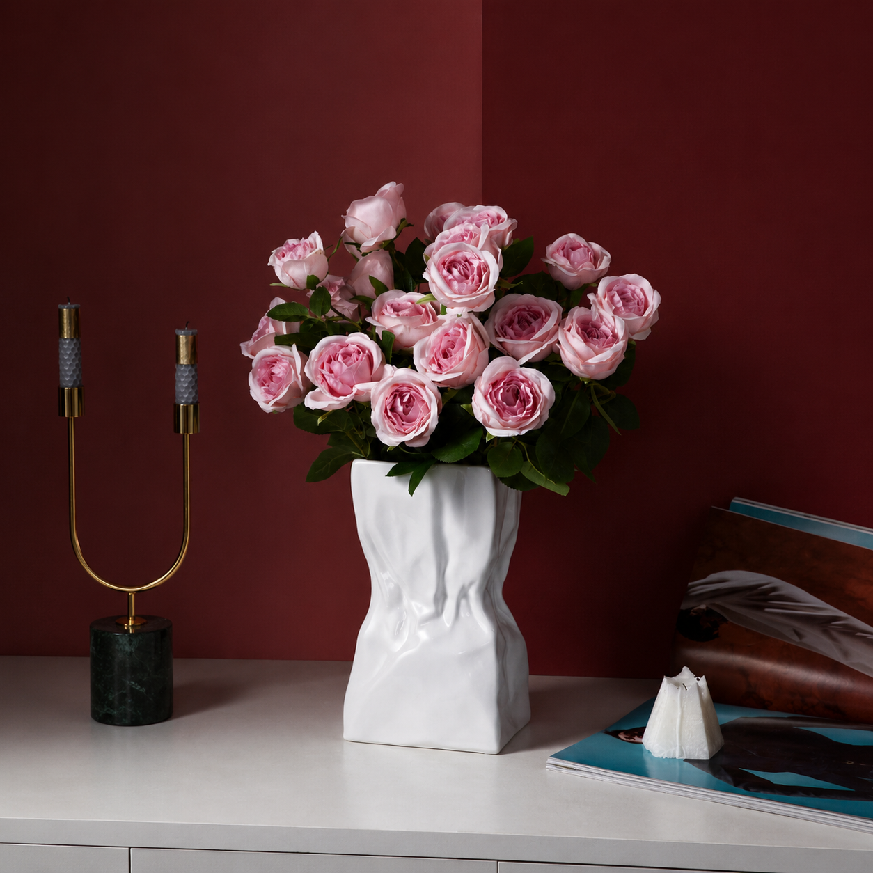 White ceramic crumpled vase with pink roses on a burgundy background