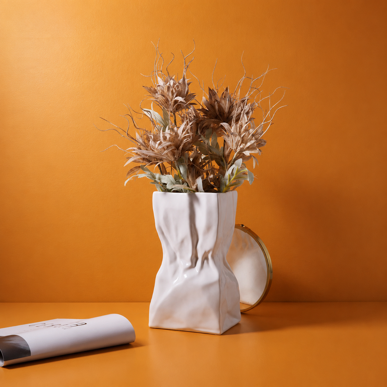 White ceramic crumpled vase with dried botanical stems on an orange background