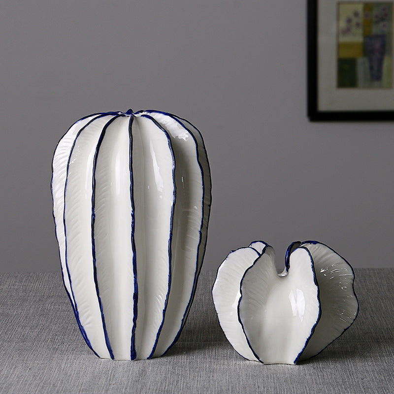 Tall and short white ceramic petal vases with blue trim on a gray tabletop