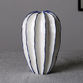Tall white ceramic petal vase with blue trim on a gray tabletop