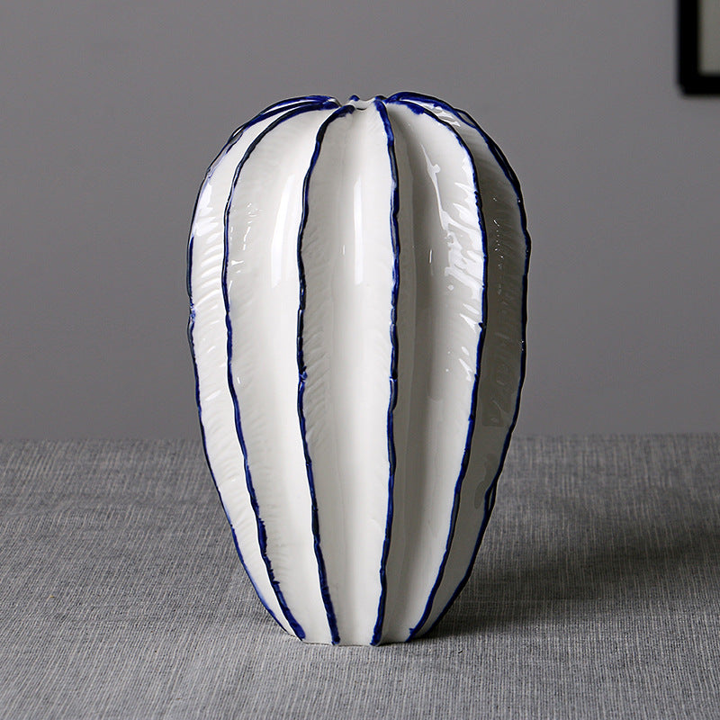 Tall white ceramic petal vase with blue trim on a gray tabletop