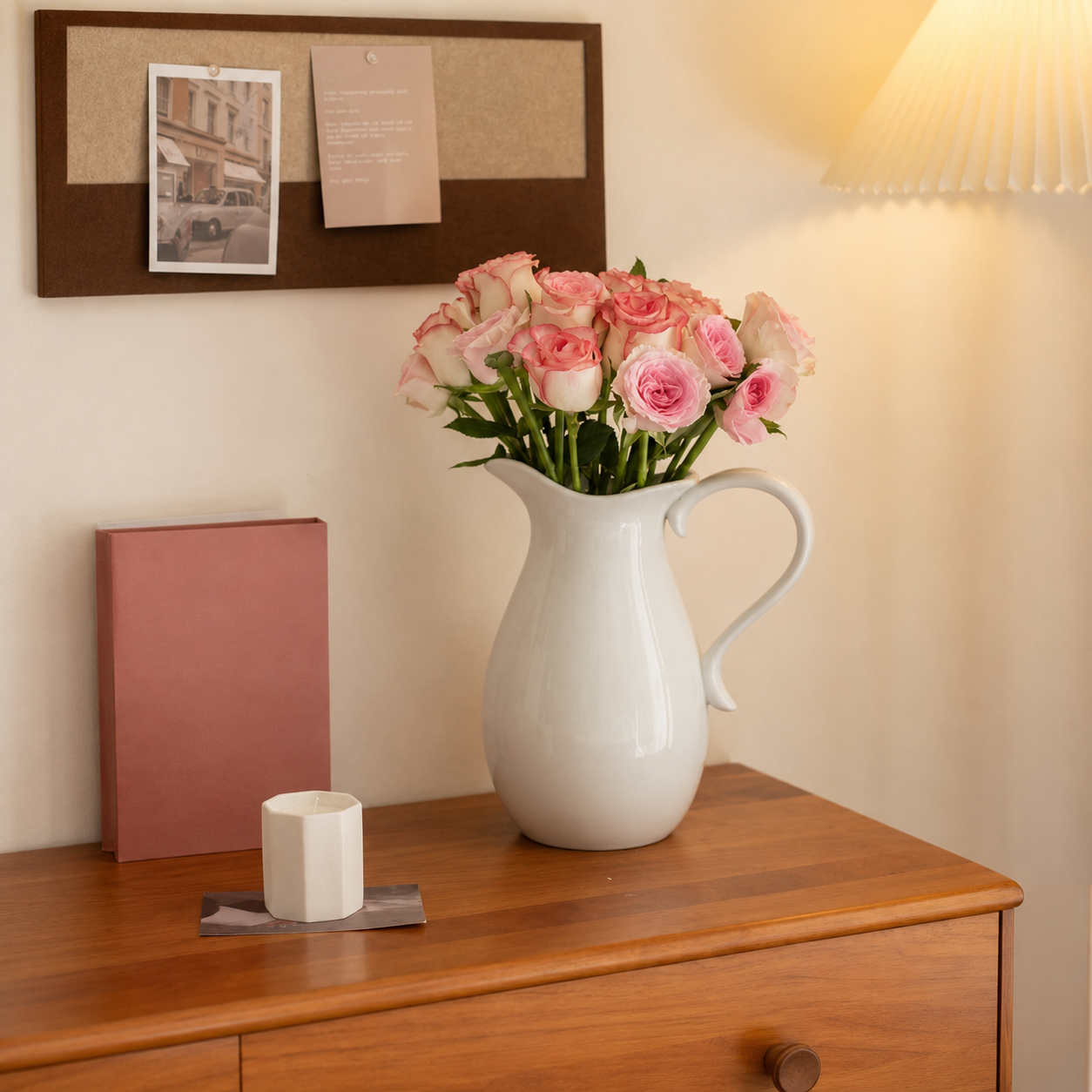 White ceramic pitcher vase with pink roses on wooden dresser