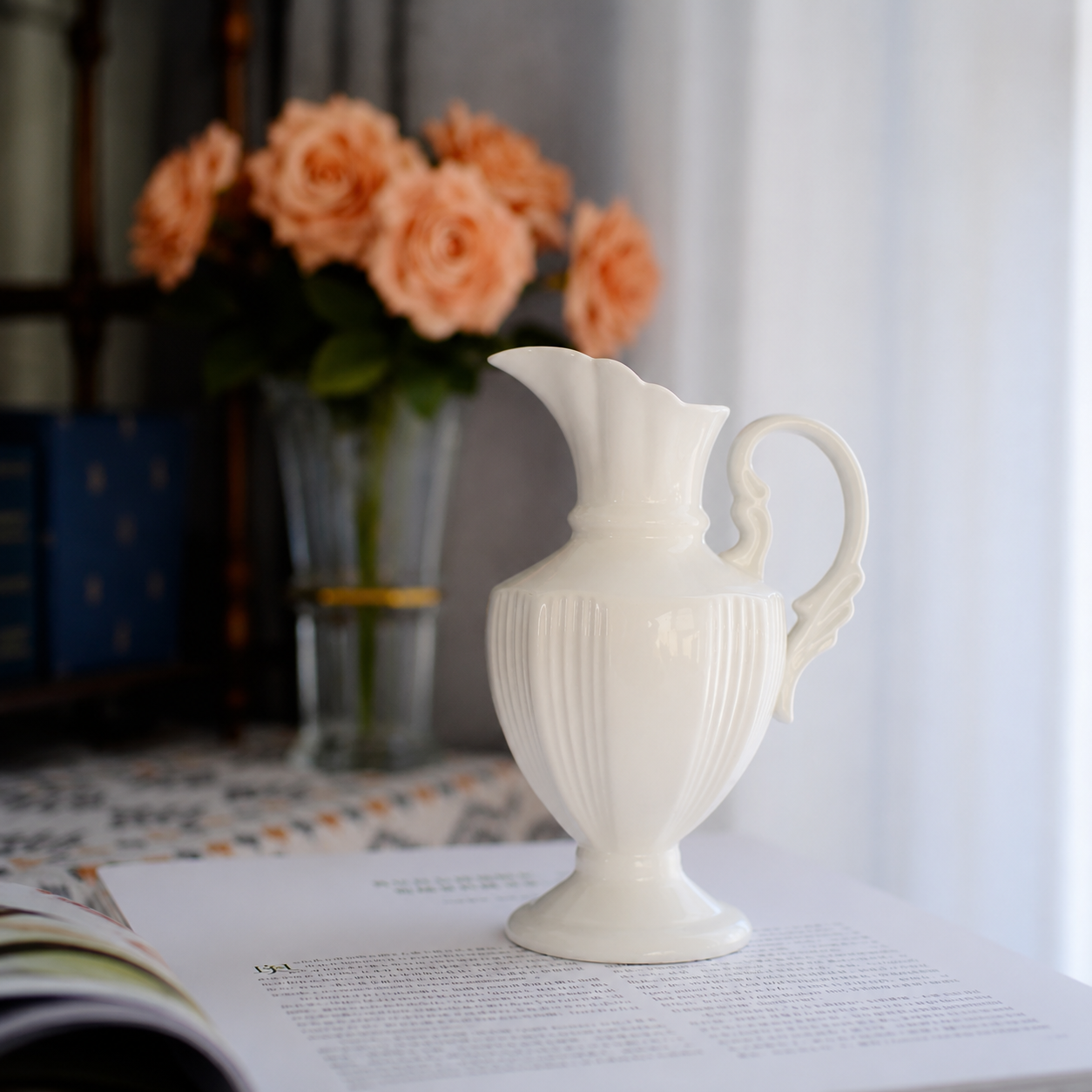 White ceramic pitcher vase styled with pink flowers on windowsill