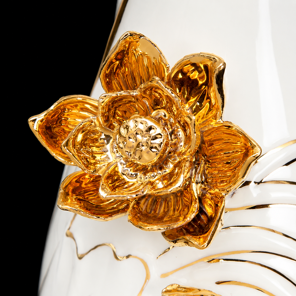 Close-up of raised 3D gold lotus flower on glossy white ceramic vase