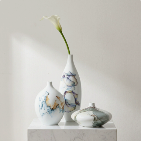 White ceramic vases with abstract glaze displayed with single floral stem