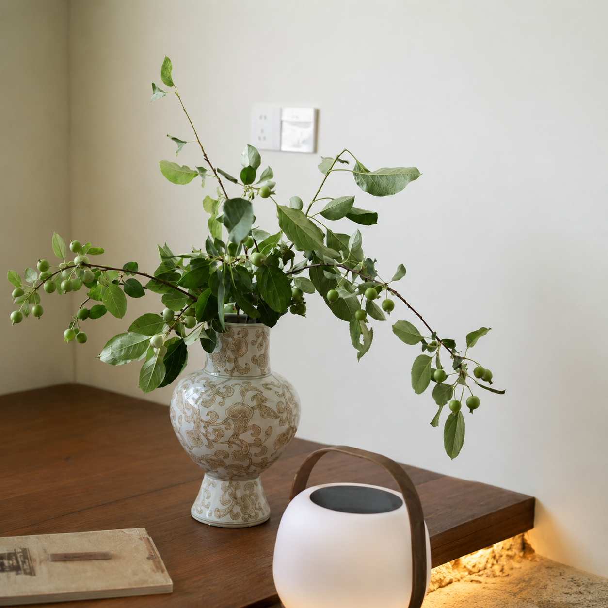 Chinoiserie ceramic vase with green branches on a wooden table in minimalist natural home decor