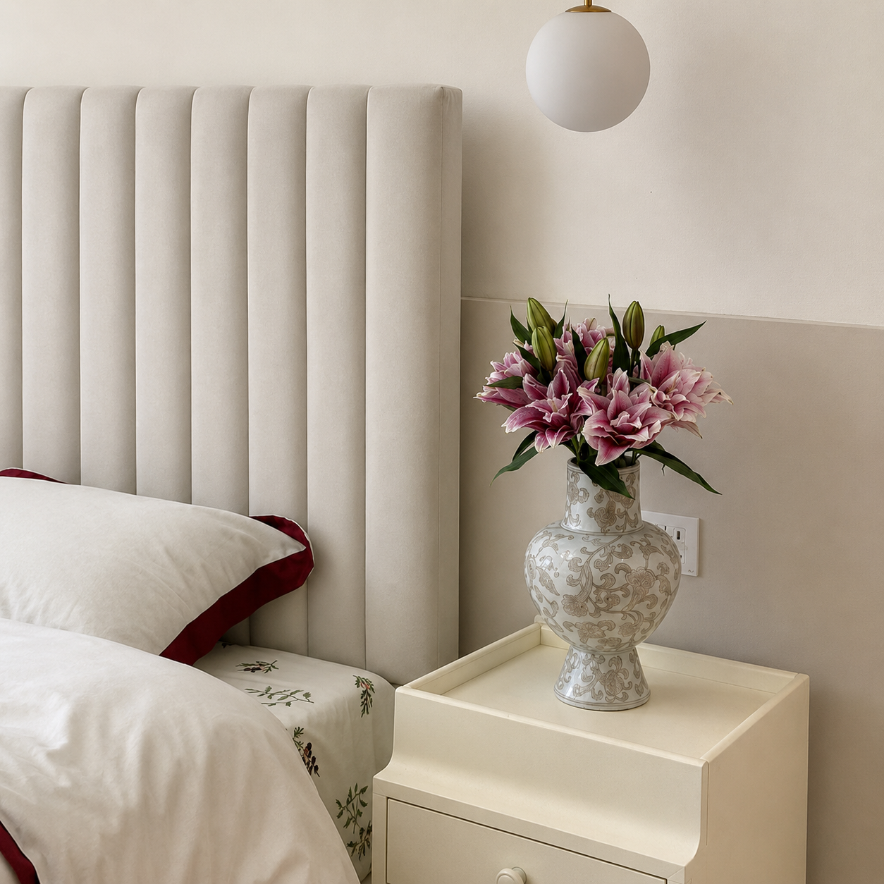White and gold ceramic vase with pink lilies on a bedside table in a soft neutral bedroom setting