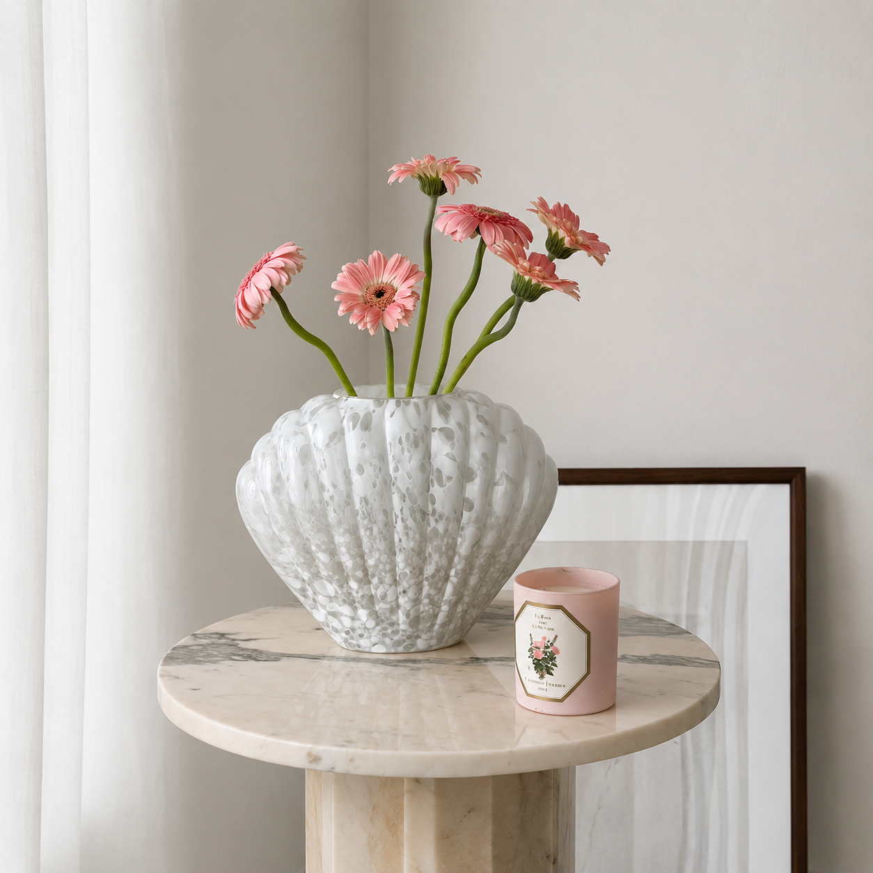 White shell-shaped glass vase with pink flowers on marble side table in neutral interior