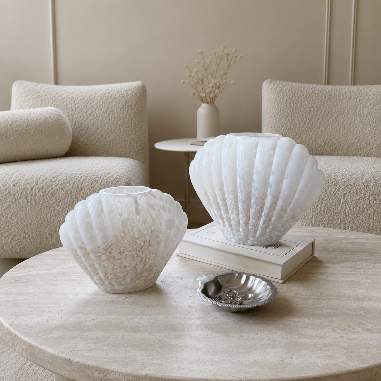 Medium and Large white shell-shaped glass vases displayed on round coffee table in neutral living room
