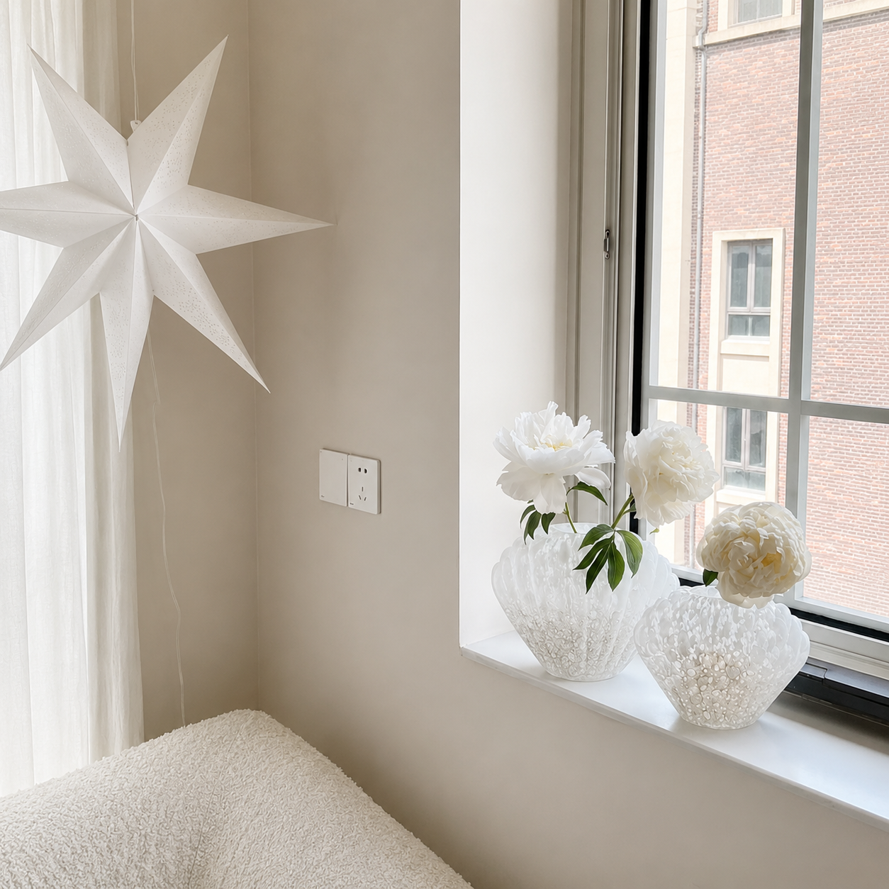 Medium and Large white shell-shaped glass vases with white flowers on window ledge in bright interior