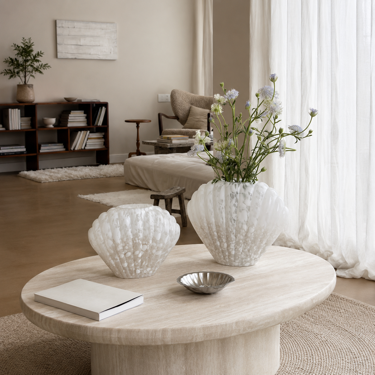 Medium and Large white shell-shaped glass vases displayed empty on round marble coffee table