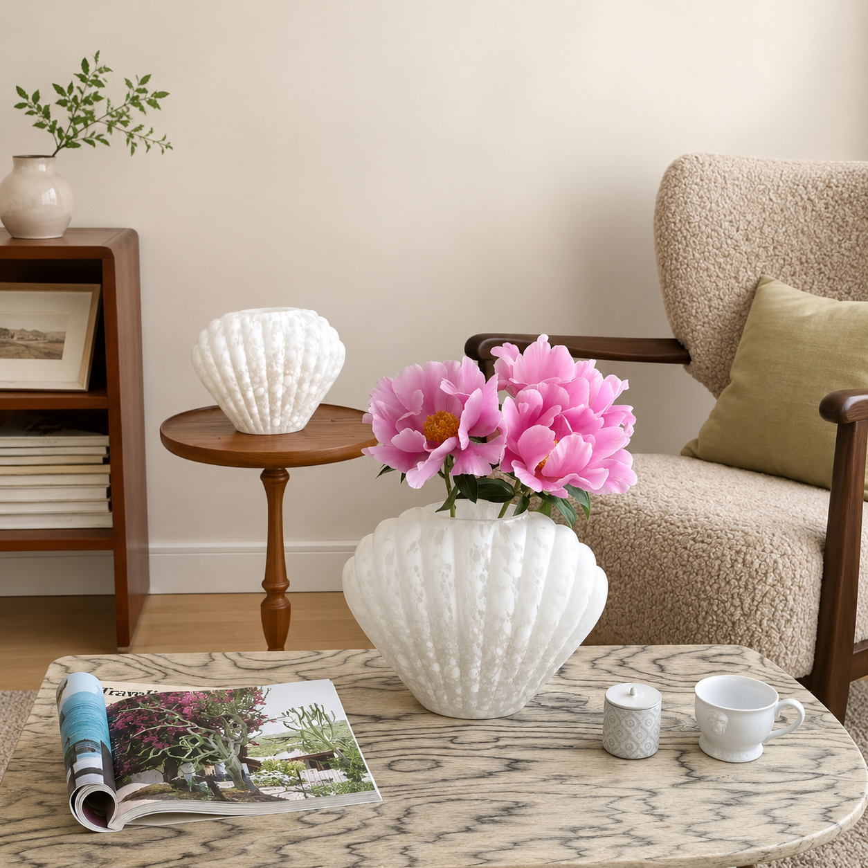 Large white shell-shaped glass vase with pink flowers on marble coffee table in cozy living room