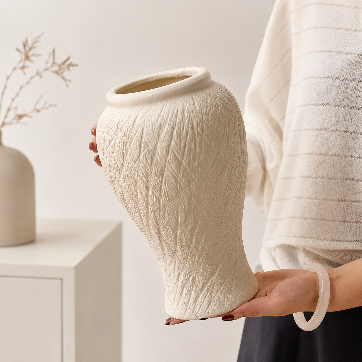 Person holding tall ivory textured ceramic vase showing scale and carved surface detail
