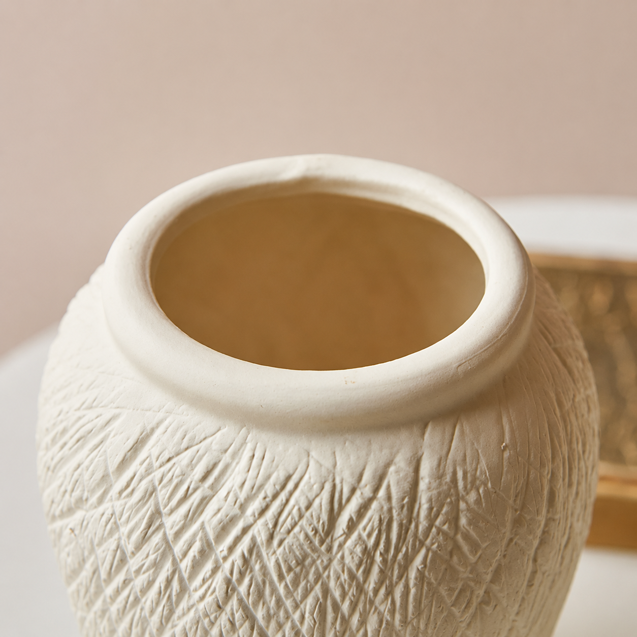 Close up of ivory textured ceramic vase opening with smooth rounded rim