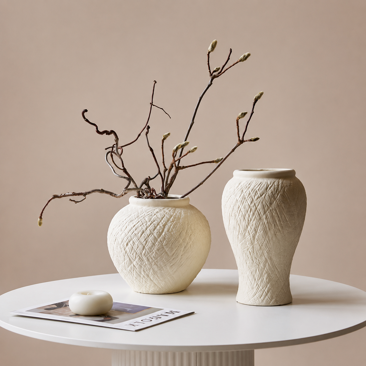 Round ivory ceramic vase and tall textured vase styled with natural branches on a white table